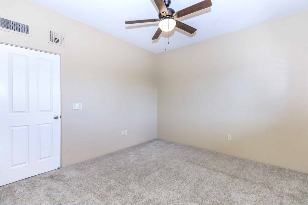 A room with a ceiling fan and a door.