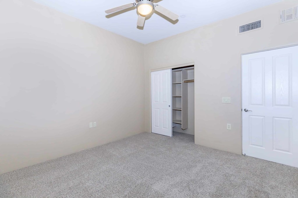 A room with a ceiling fan and a closet with a door open.