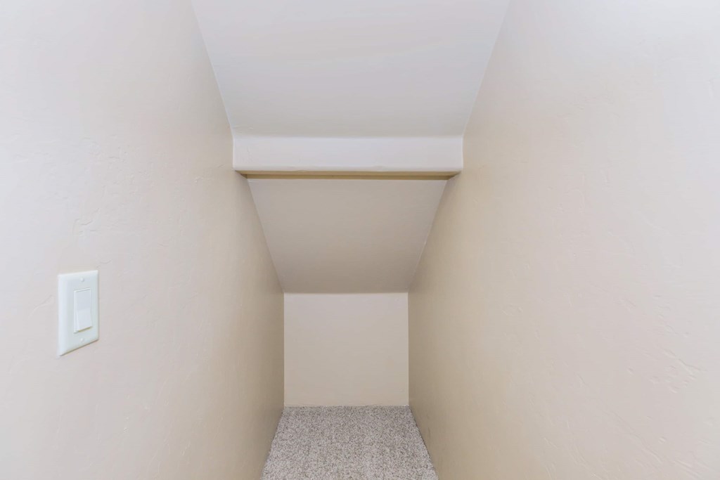 A small room with a carpeted floor and a light switch on the wall.