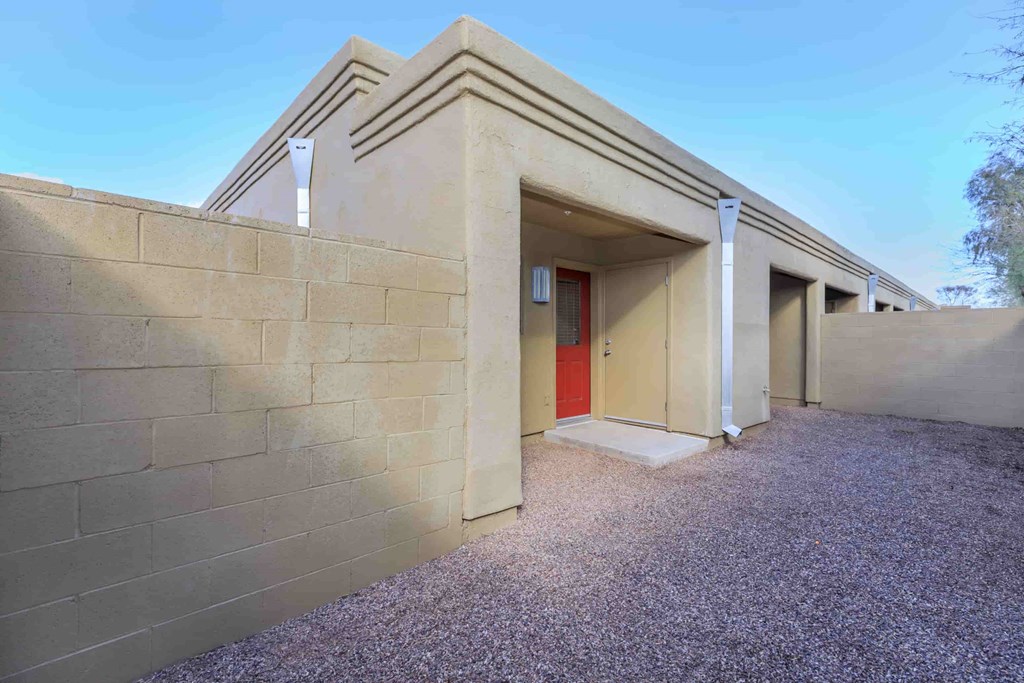 A building with a red door and a gravel driveway.