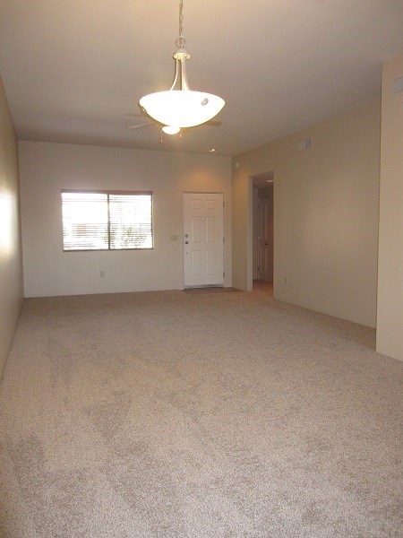 an empty living room with a ceiling fan and a window