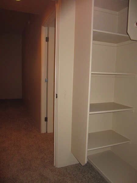 a closet with white shelves and a door