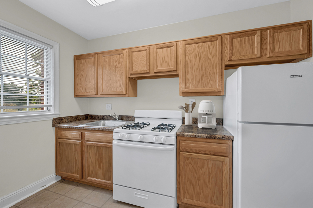 A kitchen with wooden cabinets and a white stove.