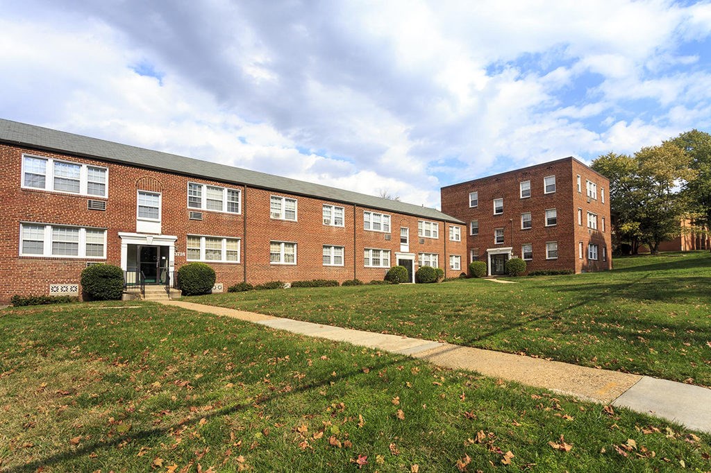 the front of a brick apartment building with a lawn