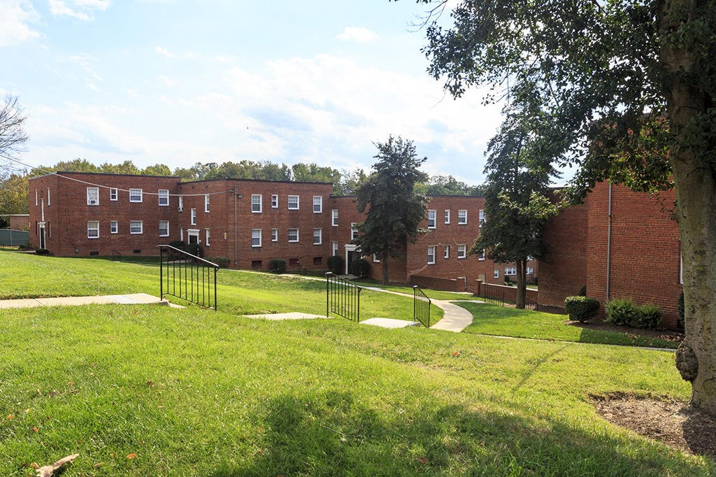 a large red brick building with a green lawn and trees