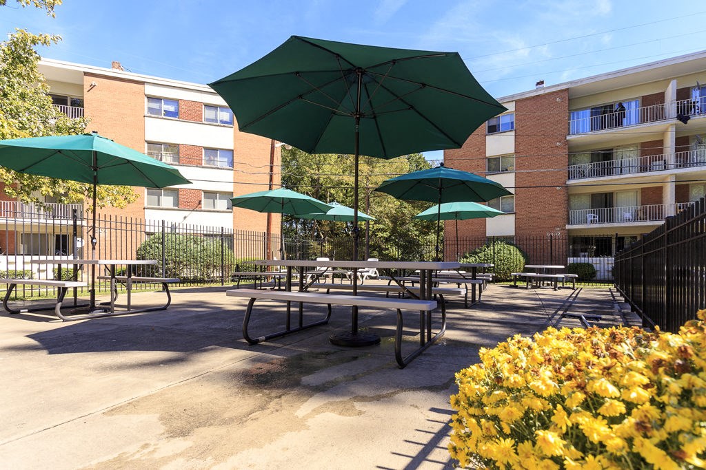 a patio with tables and umbrellas in front of an apartment building