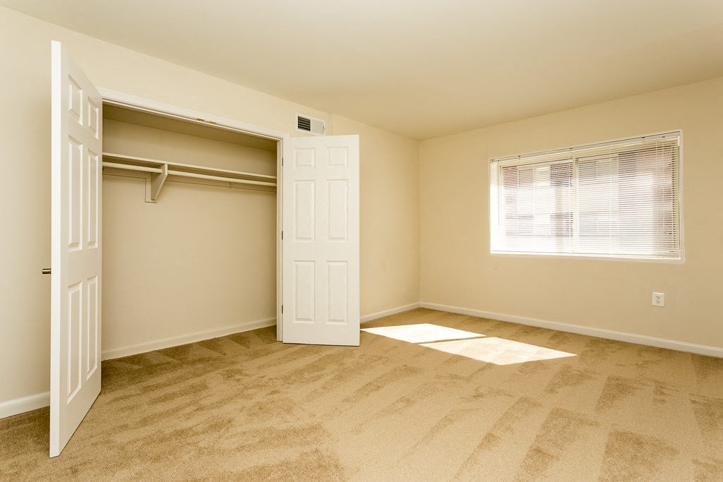 an empty bedroom with a closet and a window