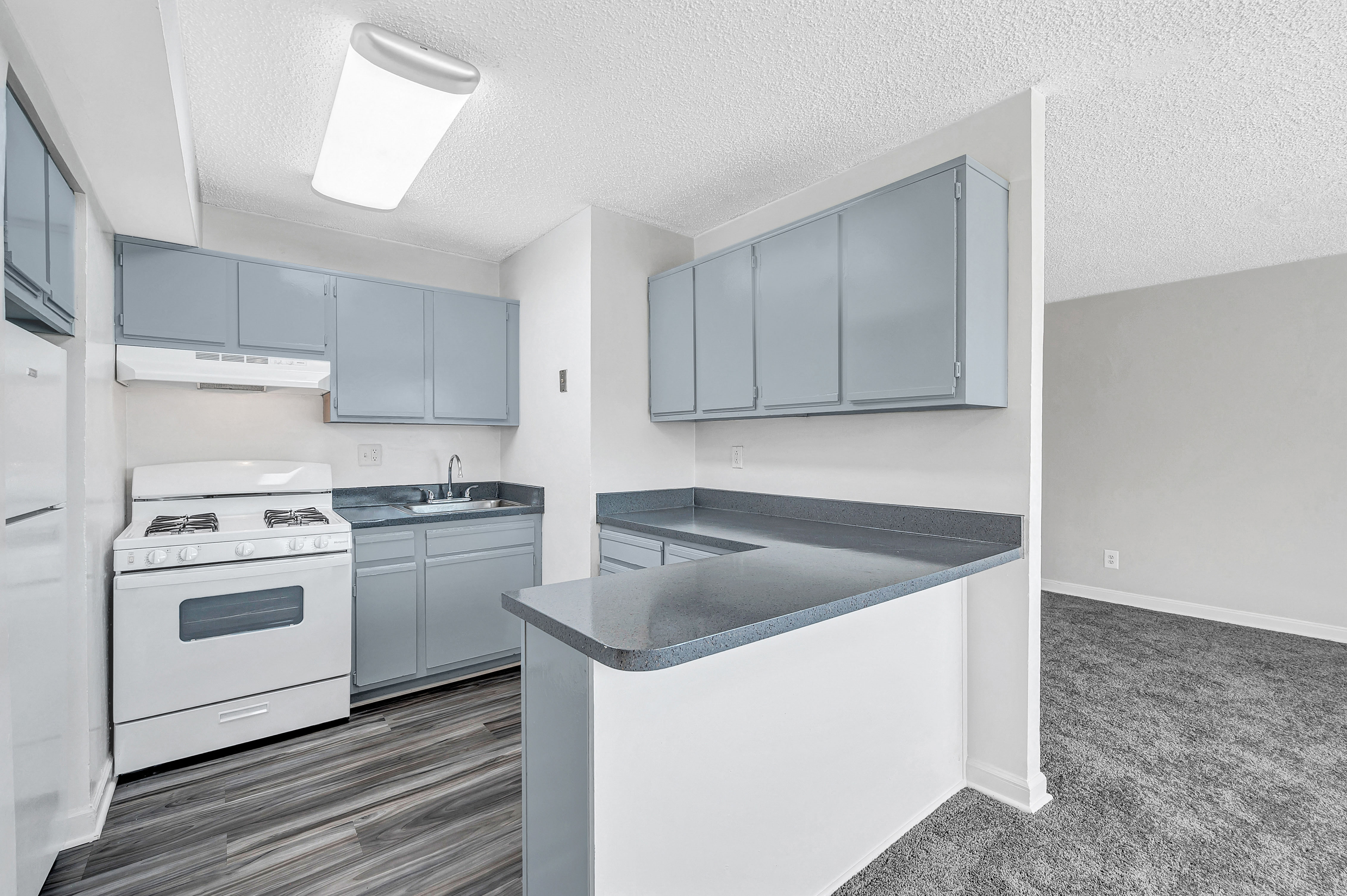 A kitchen with a white stove top oven and a white refrigerator.