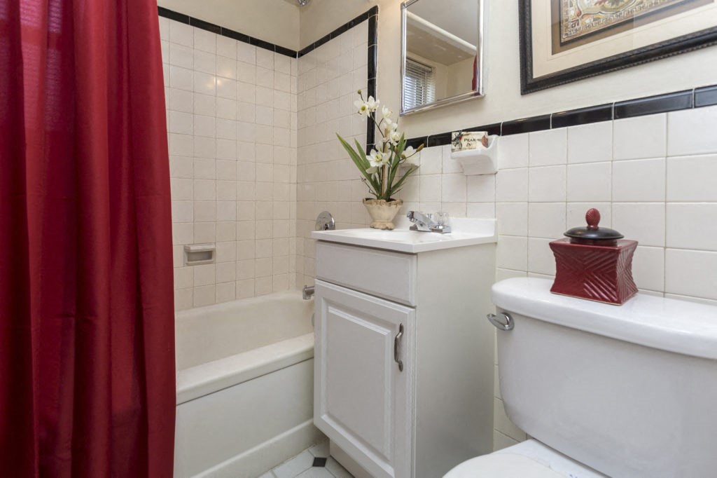 a white bathroom with a red shower curtain and a toilet and sink