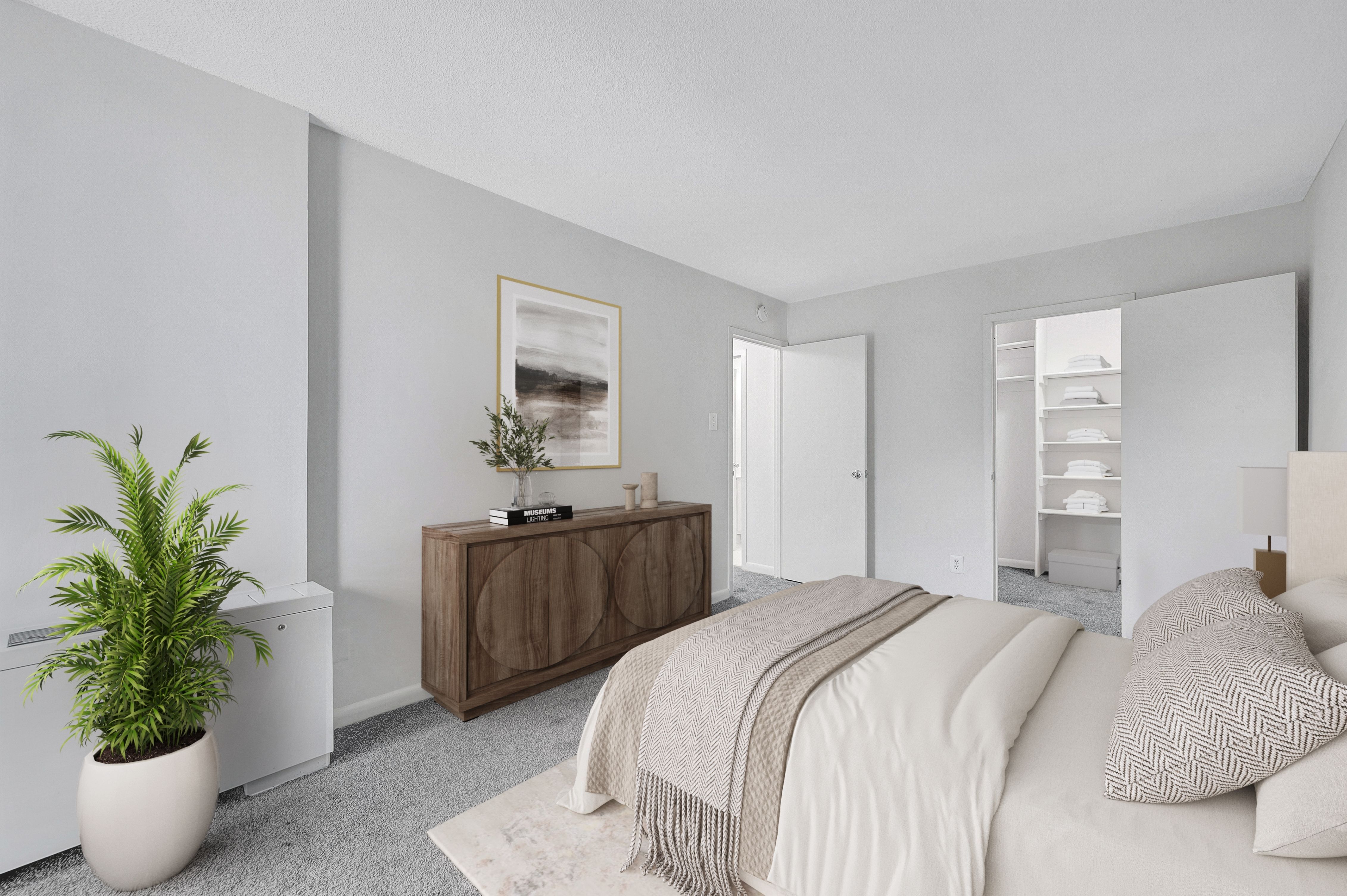 A bedroom with a bed, a plant, and a wooden cabinet.