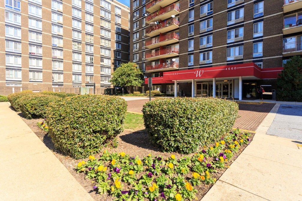 a park in front of a building with bushes and flowers