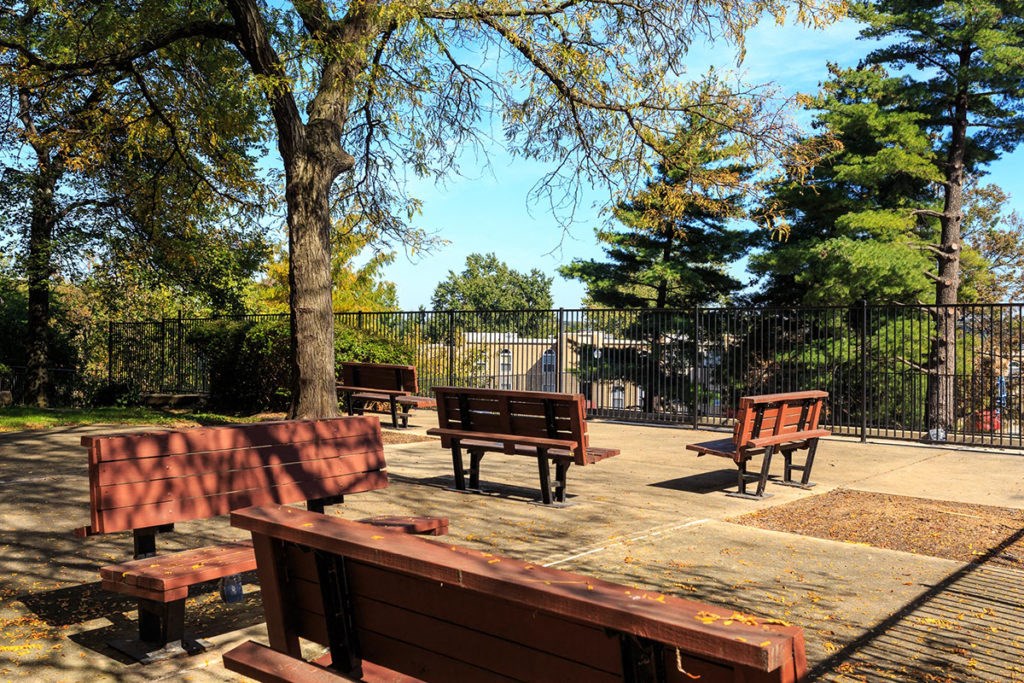 a group of benches in a park next to a fence