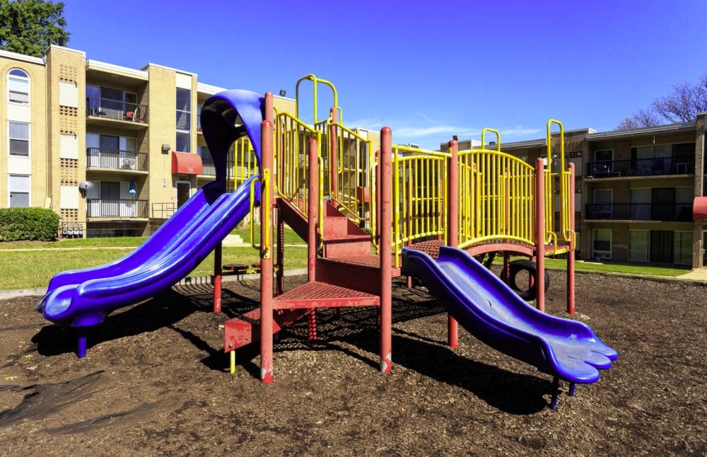 A playground with a purple slide and a red and yellow structure.