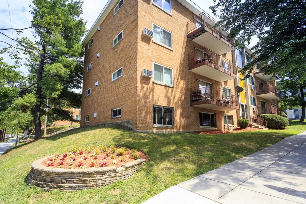 a flower garden in front of a brick apartment building