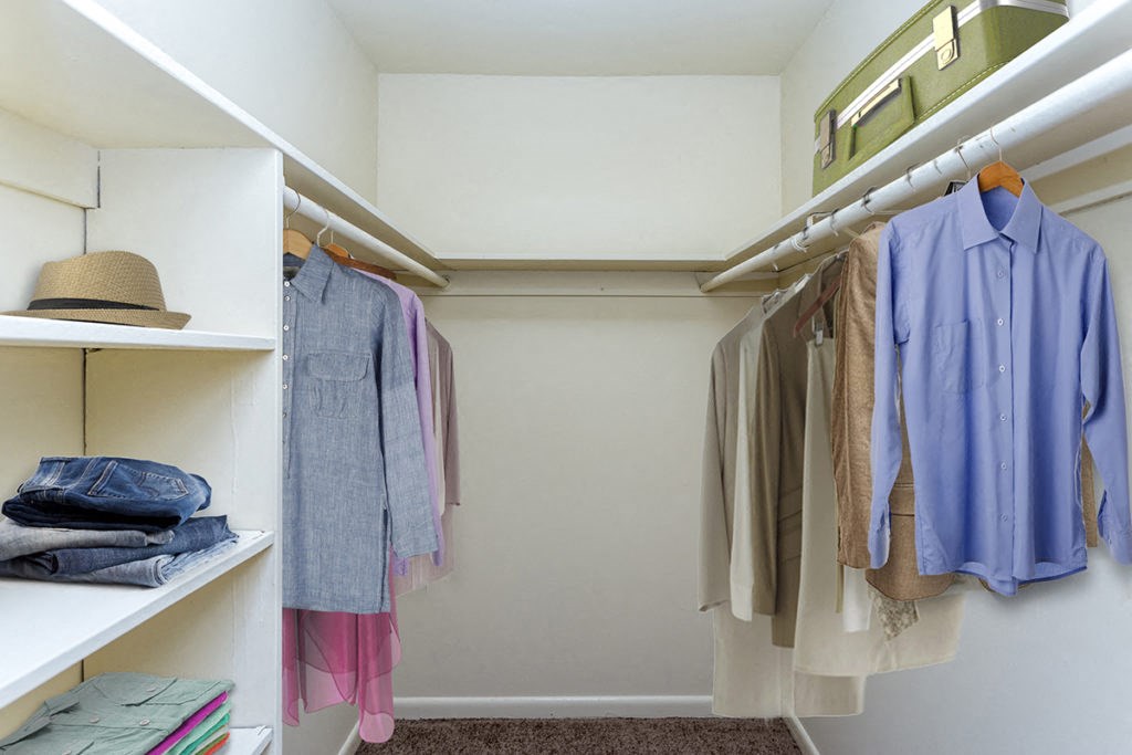 a walk in closet filled with clothes and a hat