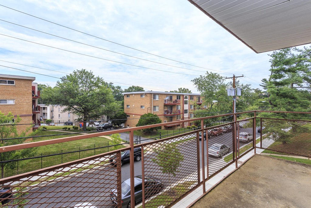 the view of a street from a balcony with a metal railing