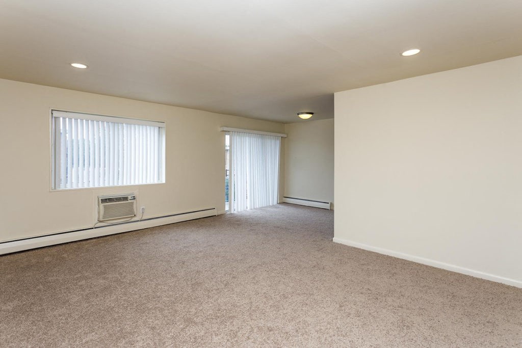 an empty living room with white walls and a window