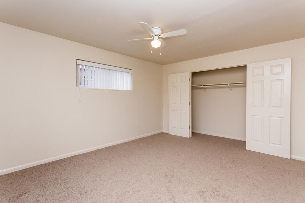 an empty bedroom with a ceiling fan and a closet