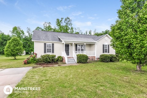 a white house with black shutters and a lawn and trees