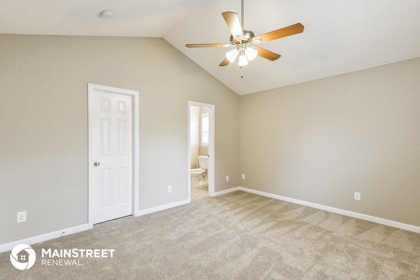 the spacious living room with carpeting and a ceiling fan