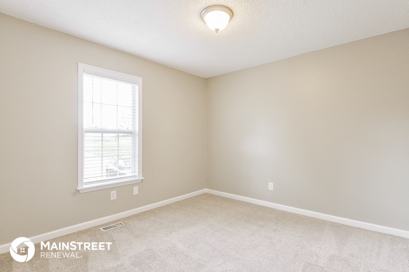 the spacious living room with carpeting and a window