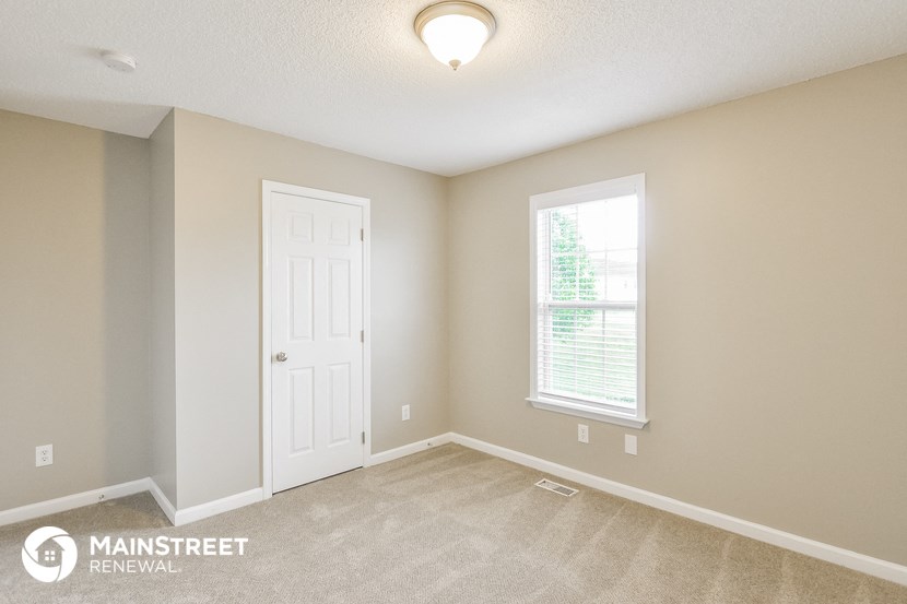 the spacious living room with a white door and a window