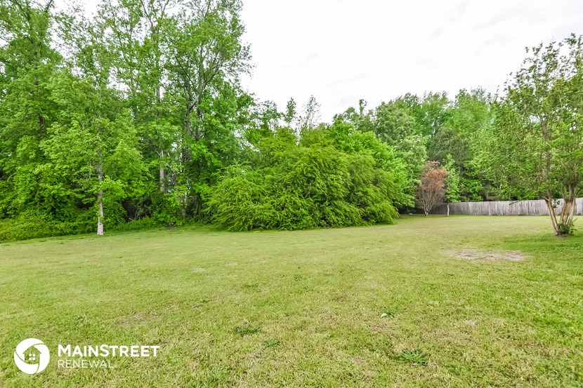 a large yard with trees and a wooden fence