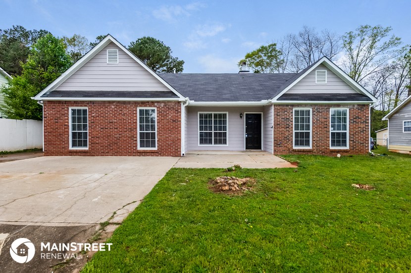 the front of a brick house with a driveway and grass