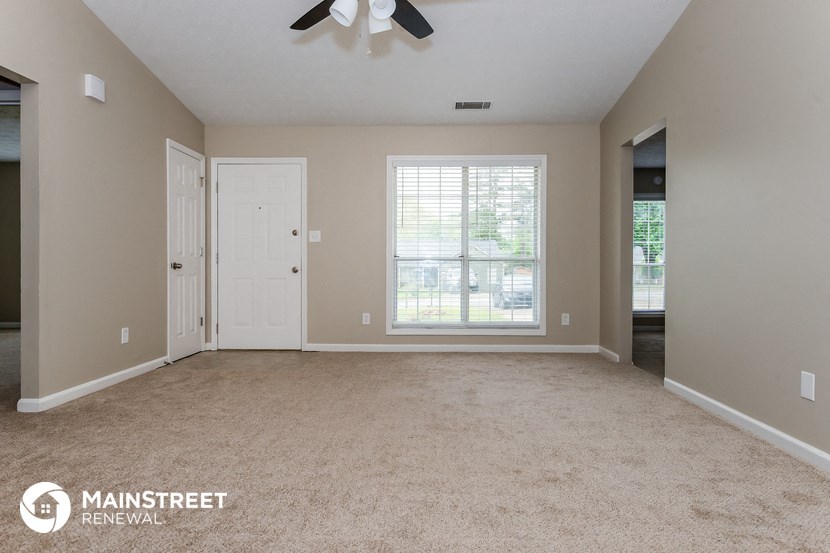 an empty living room with a ceiling fan and a window