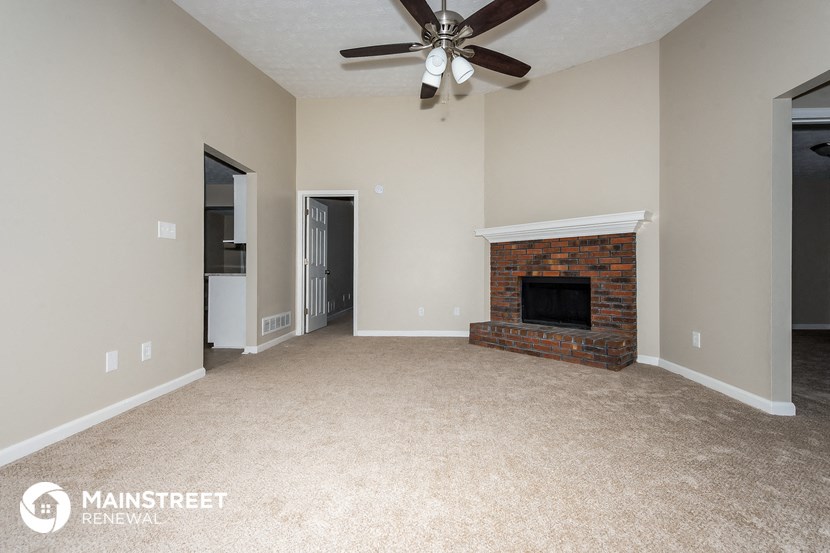a living room with a fireplace and a ceiling fan