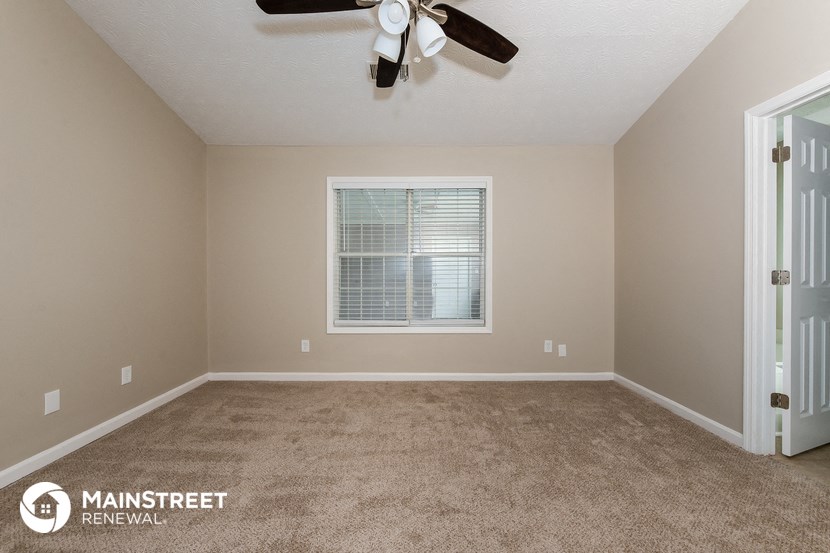 a carpeted room with a ceiling fan and a window