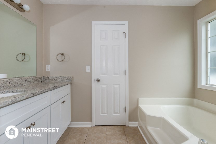 a bathroom with a tub and a sink and a white door