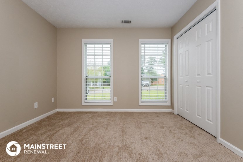 an empty living room with two windows and a white door