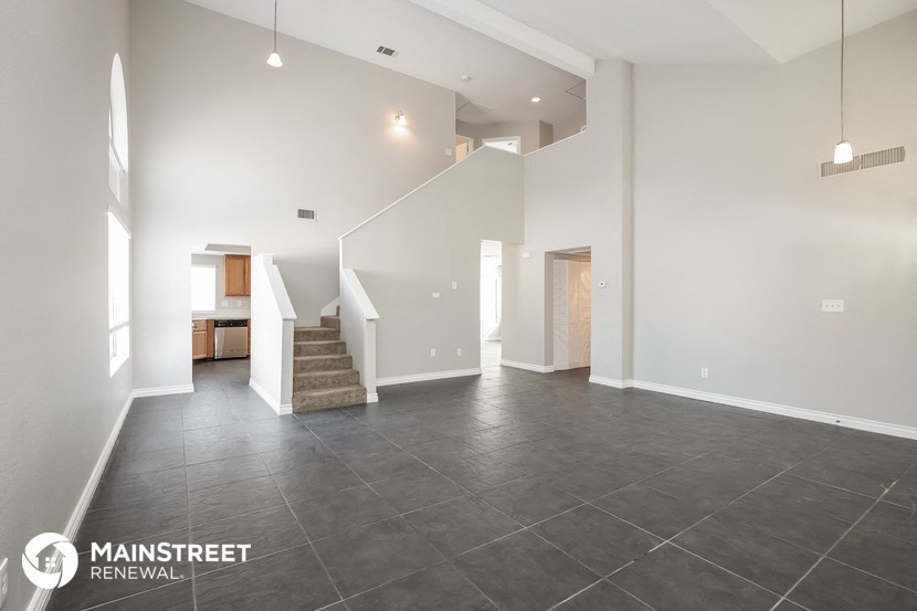 a large living room with a staircase and white walls and tile floors