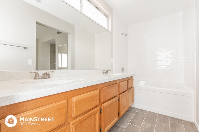 a bathroom with two sinks and a tub and a large mirror