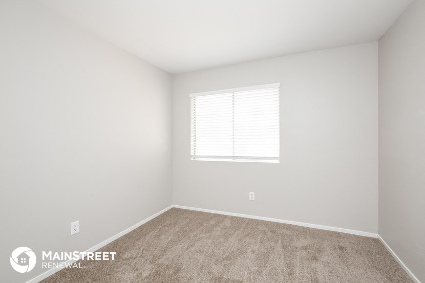 a bedroom with white walls and carpet and a window