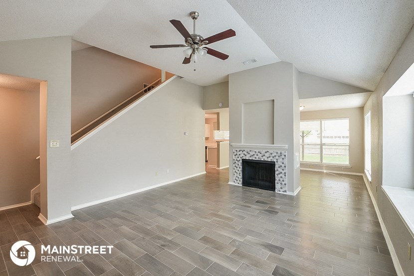 a living room with a fireplace and a ceiling fan