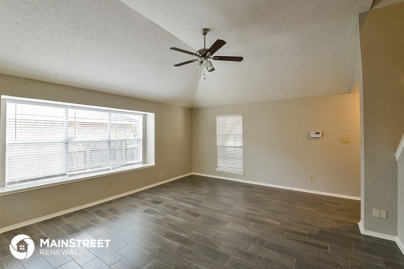 a living room with a ceiling fan and a large window