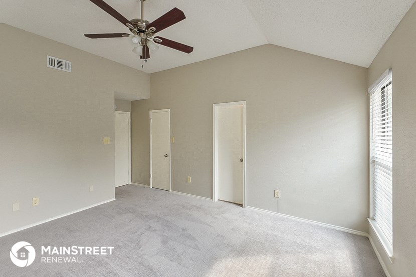 an empty living room with a ceiling fan and window