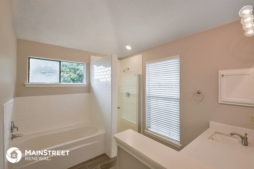 a bathroom with a tub and a sink and a window