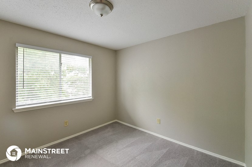 the spacious living room of a house with a large window