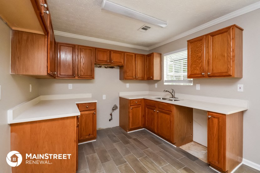 a kitchen with wooden cabinets and white counter tops and a sink