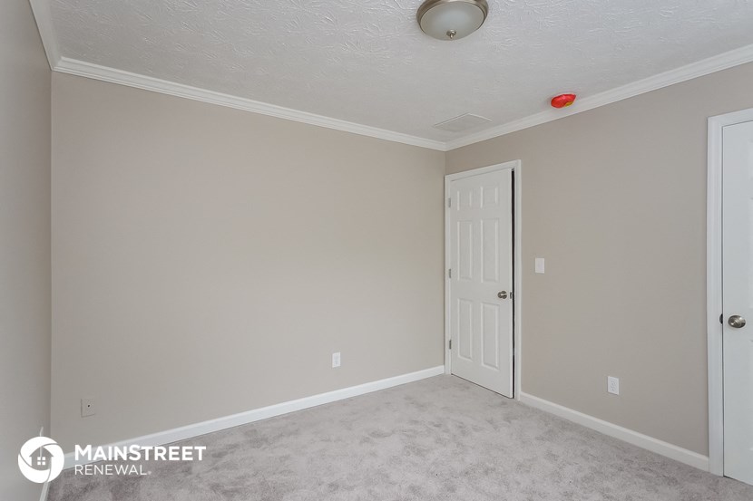 a bedroom with a white door and a carpeted floor