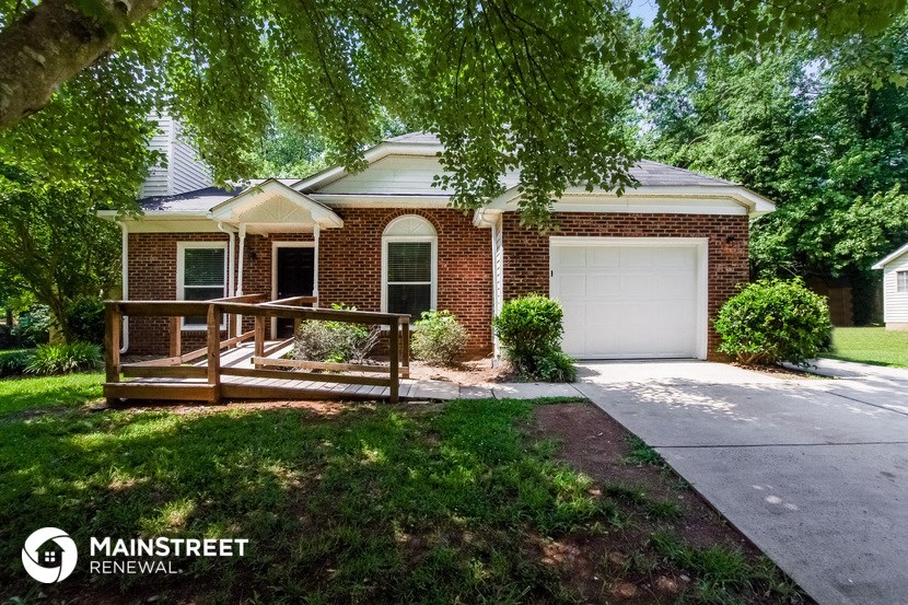 a small brick house with a porch and a white garage door