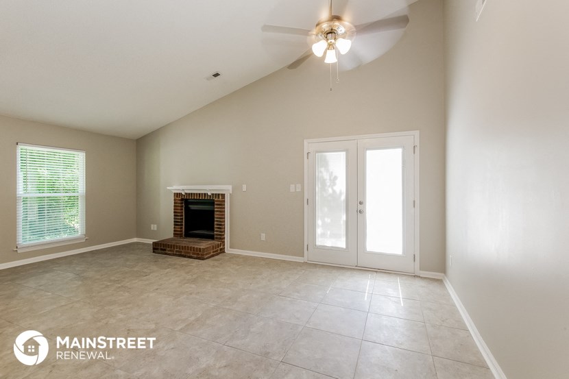 an empty living room with a fireplace and a ceiling fan