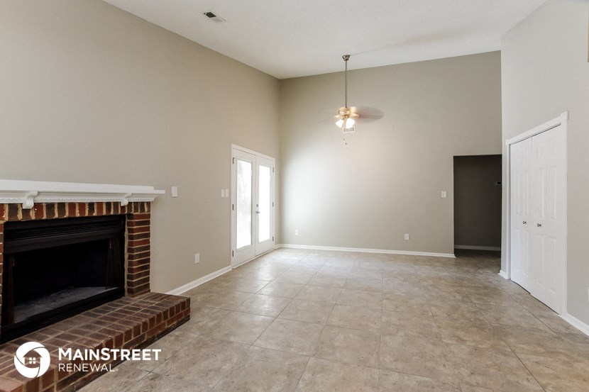 an empty living room with a fireplace and a tile floor