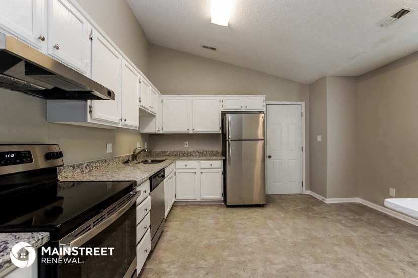 a kitchen with white cabinets and a stainless steel refrigerator