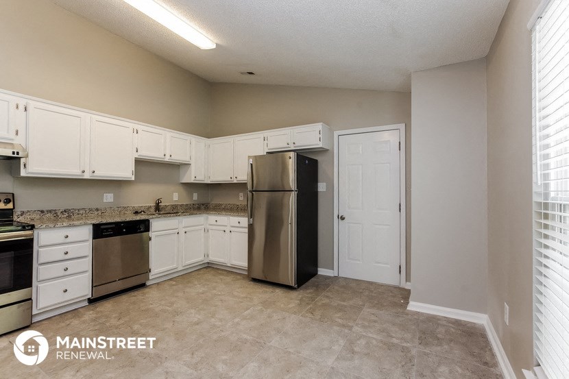 a kitchen with white cabinets and a stainless steel refrigerator