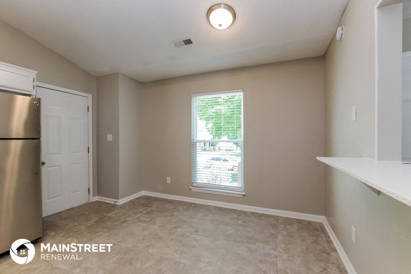 an empty living room with a window and a refrigerator