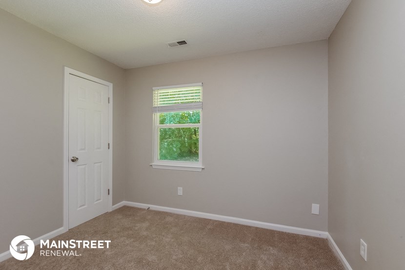 the upstairs bedroom with carpeted flooring and a window